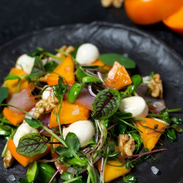 Healthy salad with persimmon, microgreens, nuts and feta cheese. Fitness nutrition.